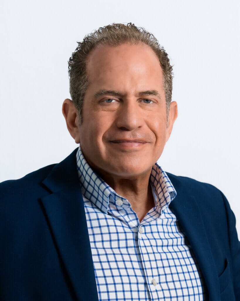 Man in a blue blazer and checkered shirt smiling confidently