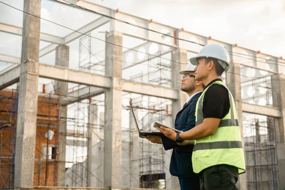 Engineers inspecting construction site with hard hats and laptop