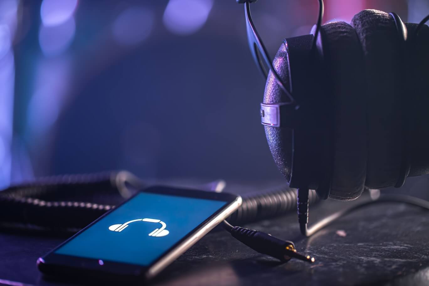 Smartphone and headphones on a table with music app open