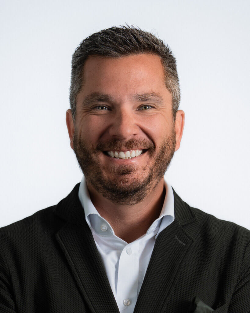 Man smiling in professional attire with a white background
