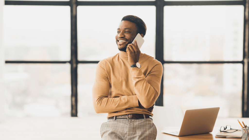 Man smiling and talking on phone in modern office setting